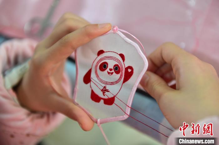 圖為一名小學(xué)生正在繡制2022年北京冬奧會吉祥物“冰墩墩”形象?！∮髟屏?攝