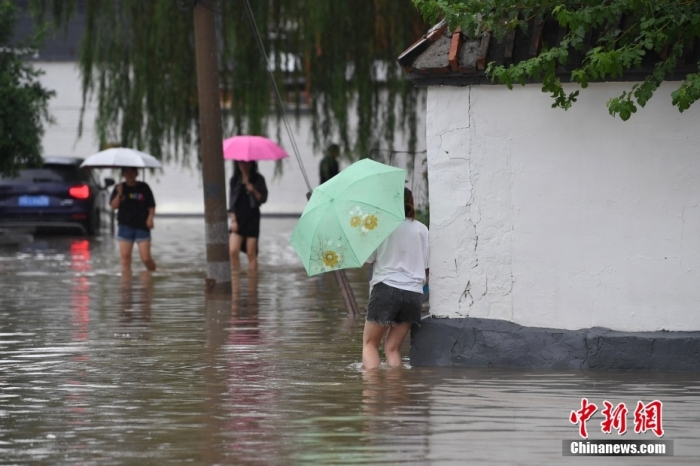 7月31日，市民行走在雨中的北京房山區(qū)瓦窯頭村。北京市氣象臺當(dāng)日10時(shí)發(fā)布分區(qū)域暴雨紅色預(yù)警信號。北京市水文總站發(fā)布洪水紅色預(yù)警，預(yù)計(jì)當(dāng)日12時(shí)至14時(shí)，房山區(qū)大石河流域?qū)⒊霈F(xiàn)紅色預(yù)警標(biāo)準(zhǔn)洪水。<a target='_blank' href='/'><p  align=