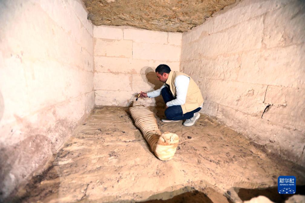 10月15日，在埃及明亞省考古現(xiàn)場，考古人員清理一座石鑿墓中的木乃伊。新華社發(fā)（艾哈邁德·戈馬攝）