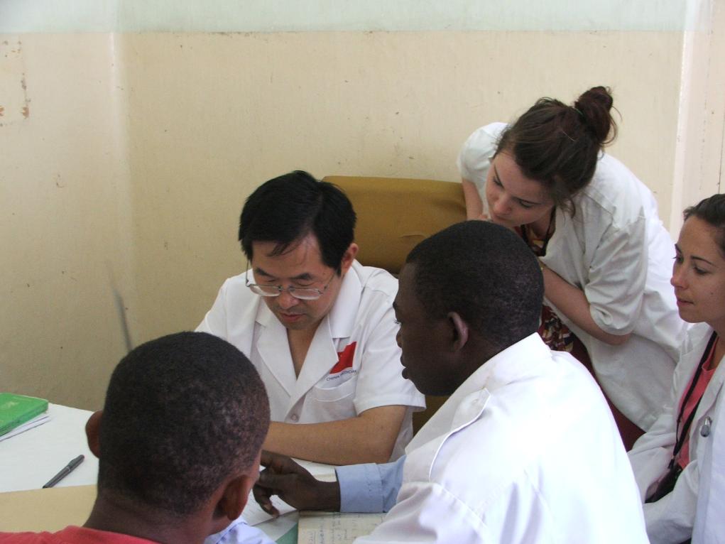 2011年7月22日，在坦桑尼亞桑給巴爾納茲莫加醫(yī)院外科門診，中國(guó)第24批援桑給巴爾醫(yī)療隊(duì)隊(duì)長(zhǎng)盧建林為當(dāng)?shù)鼗颊咴\治并帶教實(shí)習(xí)生。新華社發(fā)（國(guó)家衛(wèi)生健康委供圖）