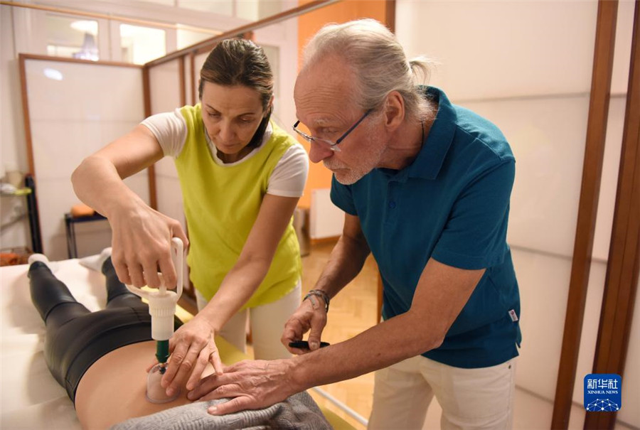 12月12日，在奧地利維也納，科格勒醫(yī)生（右）和助手在為病人進(jìn)行拔罐治療。新華社記者 賀燦鈴 攝