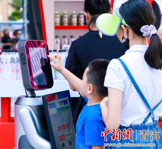 圖為一名小朋友正在和機(jī)器人“志愿者”進(jìn)行互動(dòng)。 沐聞 攝