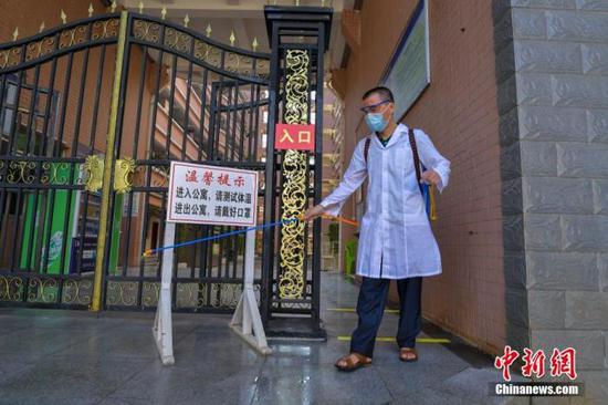 資料圖：?？诮?jīng)濟(jì)學(xué)院的工作人員在學(xué)生宿舍樓入口消毒。 中新社記者 駱云飛 攝