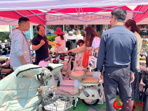 某電動(dòng)自行車(chē)品牌工作人員向消費(fèi)者介紹以舊換新相關(guān)情況。人民網(wǎng)記者 杜燕飛攝