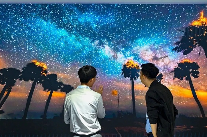 長春光博會希達(dá)電子展區(qū)，一位工作人員正在給一位觀眾講解。（長春新區(qū)供圖）