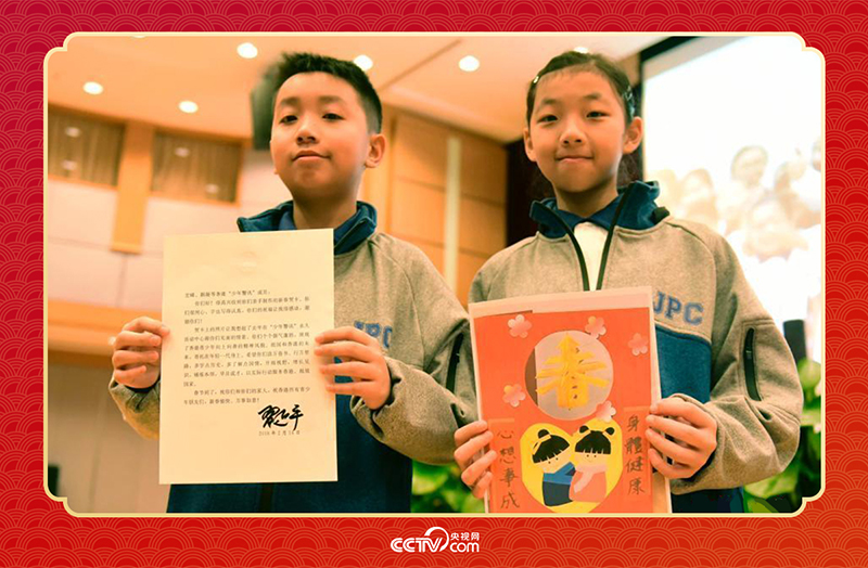 圖為香港“少年警訊”成員郭宏晞（左）展示習(xí)主席回信、羅顥凝（右）展示送給習(xí)主席的賀卡并合影。