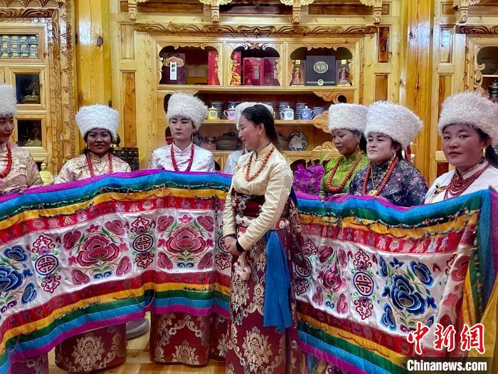 圖為女性展示村民自發(fā)繡制的“百米五彩哈達”?！±钣穹?攝
