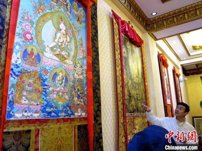 圖為完德尖措展示熱貢龍樹畫苑內(nèi)的唐卡?！?zhí)砀?攝