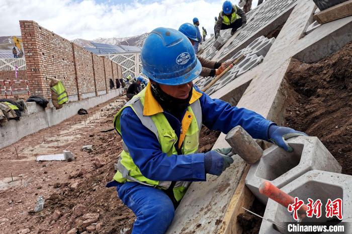 圖為光伏發(fā)電項(xiàng)目施工區(qū)工人在護(hù)坡鋪設(shè)空心磚?！±铍h 攝