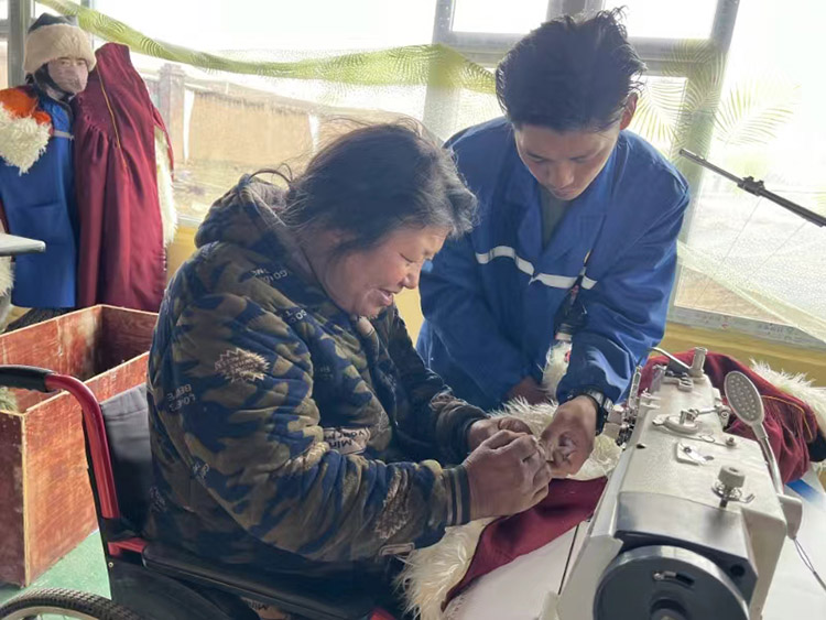 扎西奪爾登幫助殘疾員工裁剪。阿壩州文明辦供圖