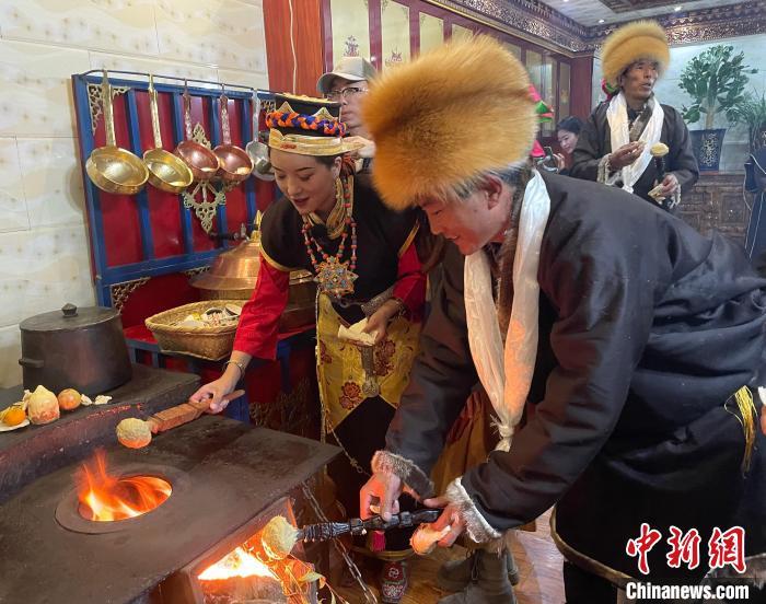 圖為人們在火上烤節(jié)日美食“結(jié)達”?！∪轿木?攝