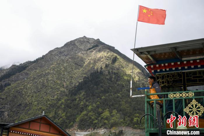 村民站在樓房上觀望?！钊A峰 攝