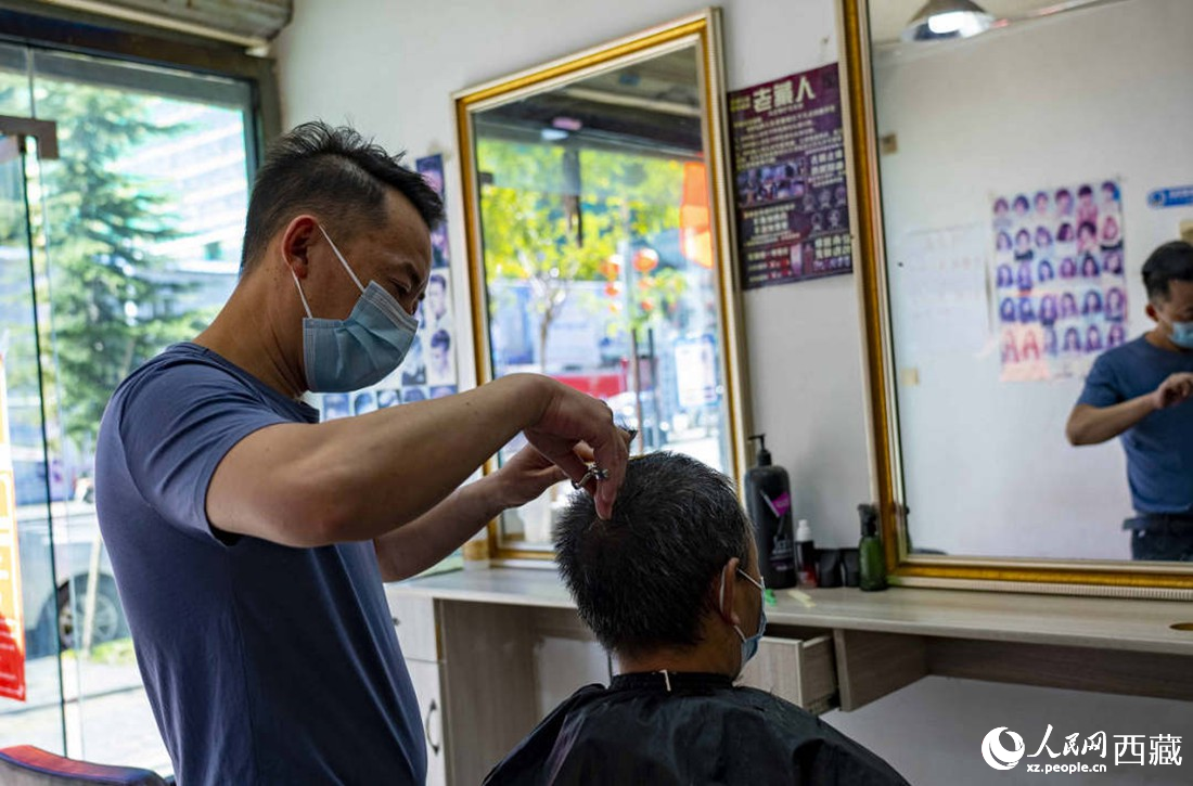 理發(fā)店老板為顧客理發(fā)。次仁羅布 攝