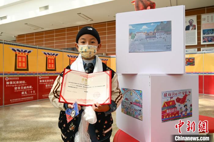 圖為一名獲獎學(xué)生與自己的繪畫作品合影?！≮w朗 攝