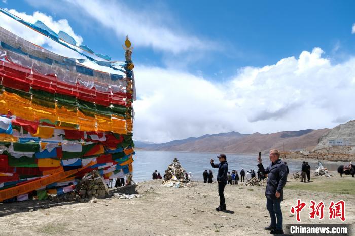 進(jìn)藏參訪嘉賓在羊湖畔拍攝經(jīng)幡?！〗w波 攝