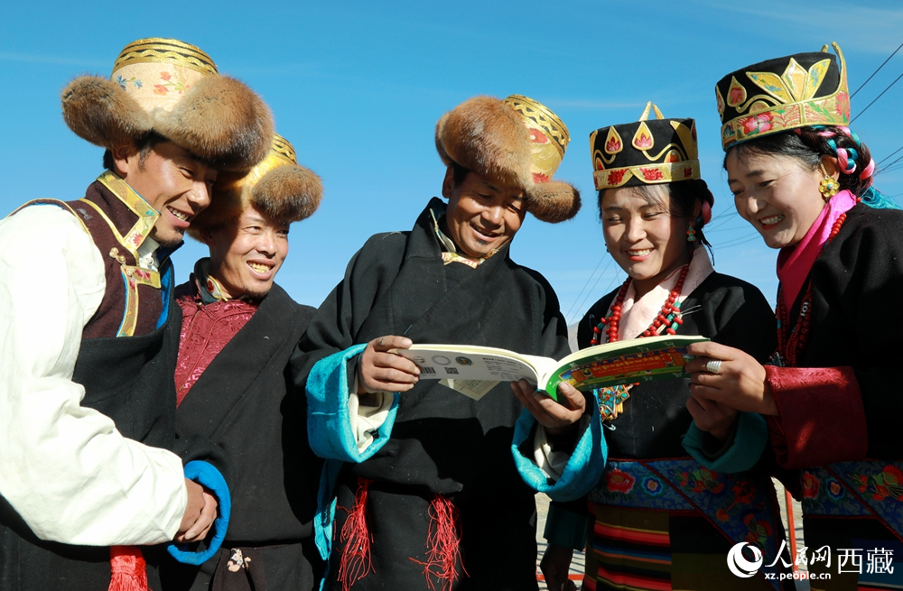 鄉(xiāng)親們身著民族盛裝，圍站在一起認(rèn)真翻看日歷，共話農(nóng)事安排與時(shí)節(jié)規(guī)律，笑容洋溢傳遞豐收期盼。人民網(wǎng)記者 吳雨仁攝