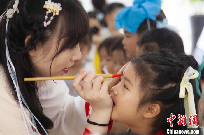 圖為老師在孩子們額頭上點上雄黃，驅(qū)邪辟禍?！《^生 攝