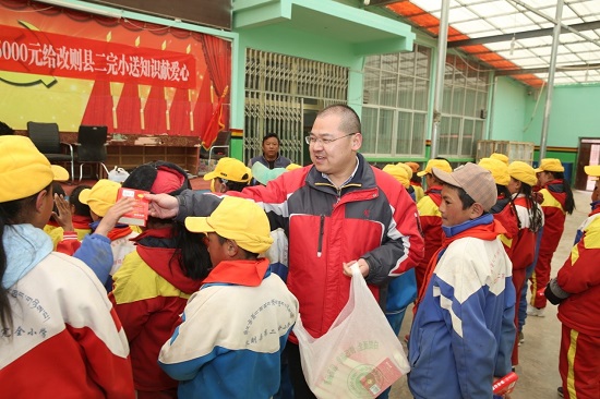 段玉平為孩子們分發(fā)愛心人士捐贈的新華字典 圖片來源：央廣網.jpg